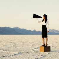 A woman standing on a box and holding a megaphone