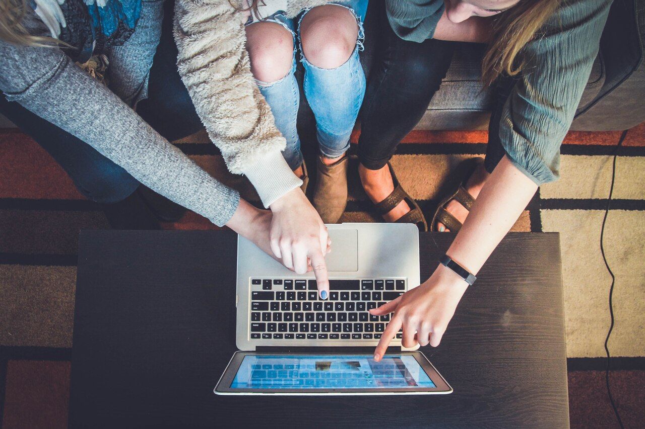 three people pointing the laptop