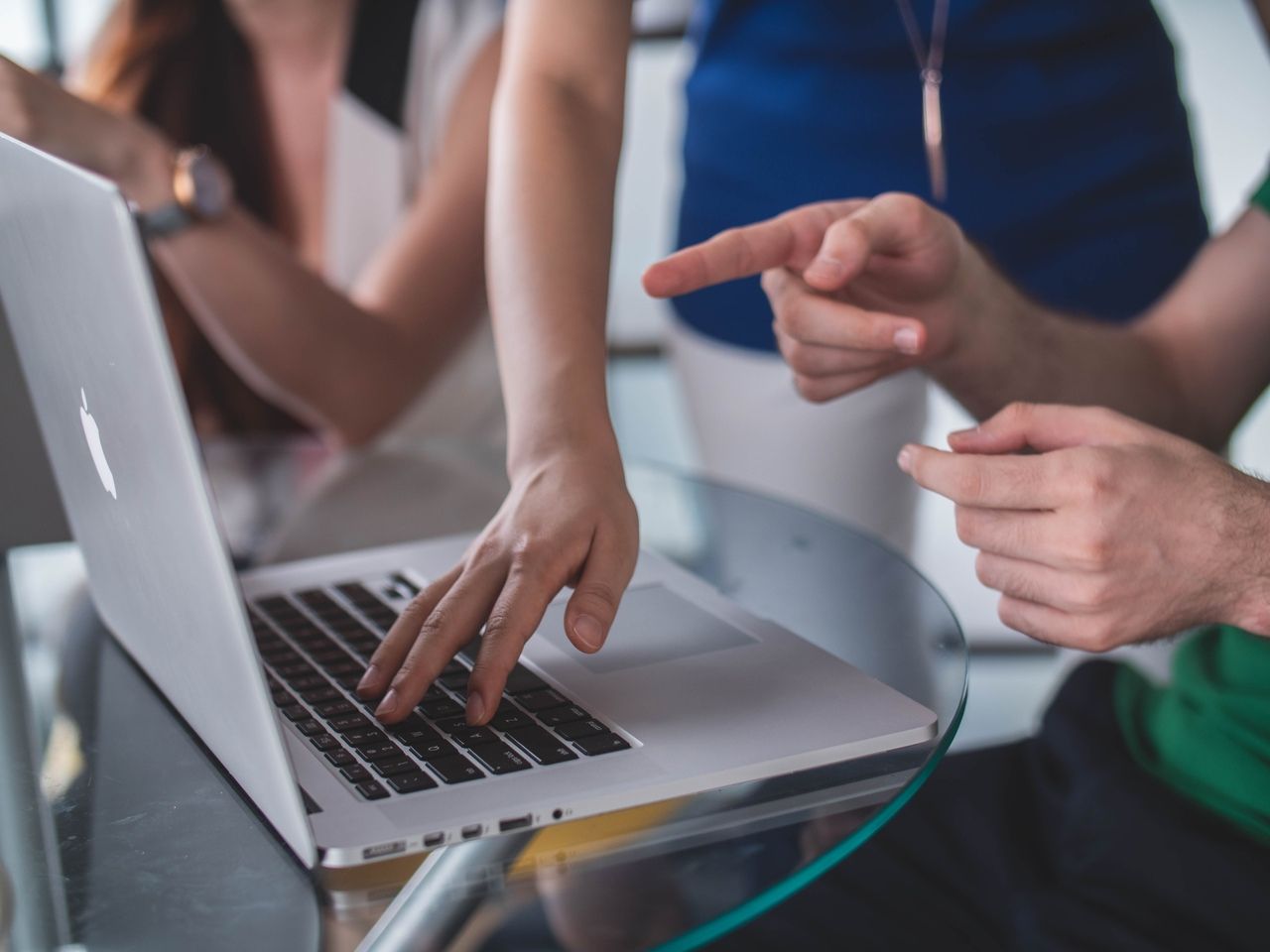 people touching and pointing Macbook laptop